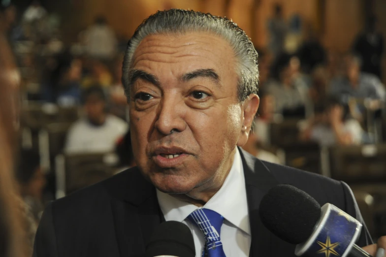 a man in a suit and tie sitting down in front of a microphone