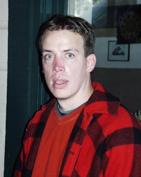 a man wearing a red and black checked jacket