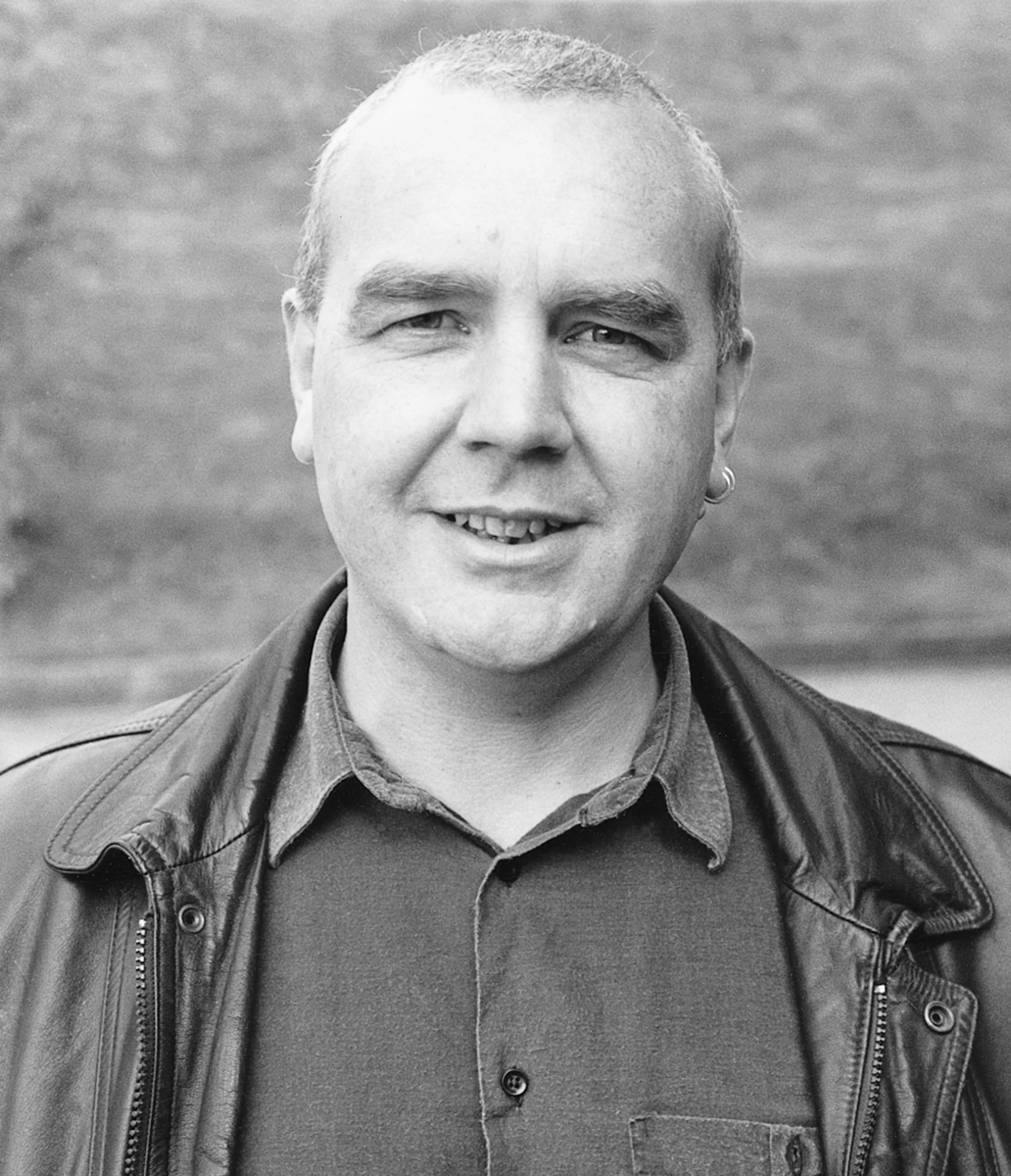 black and white pograph of man in leather jacket smiling