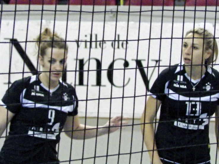 two girls are playing volleyball inside a net