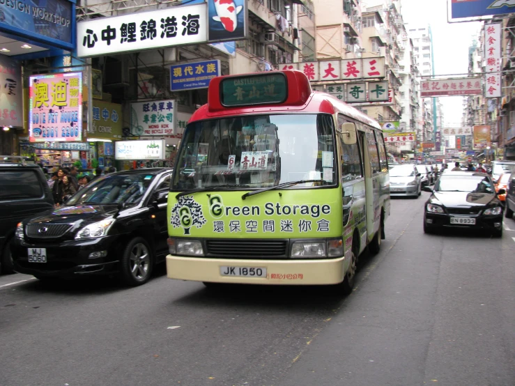 a city street lined with lots of traffic with a small bus in the front