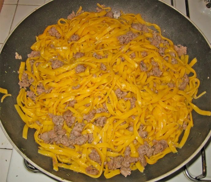 an iron wok with cheese and meat in it