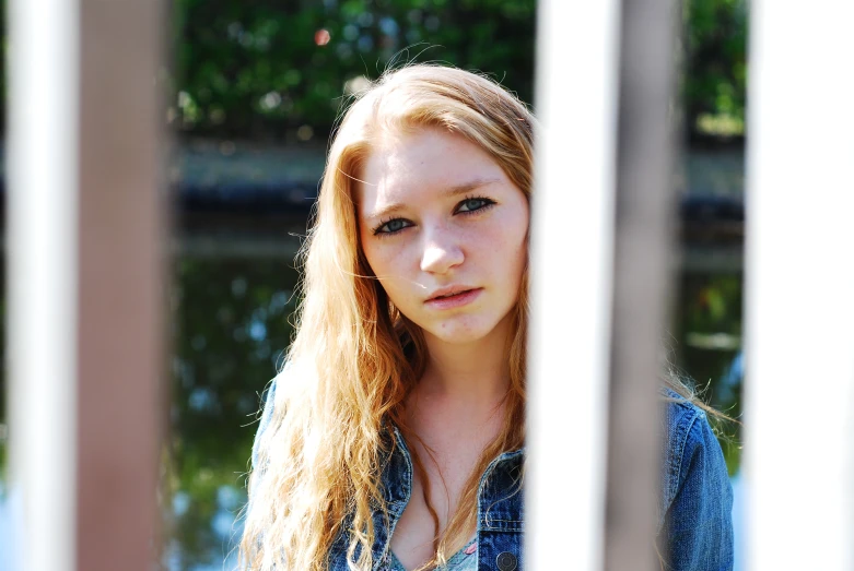 a beautiful young lady standing next to a wooden pole