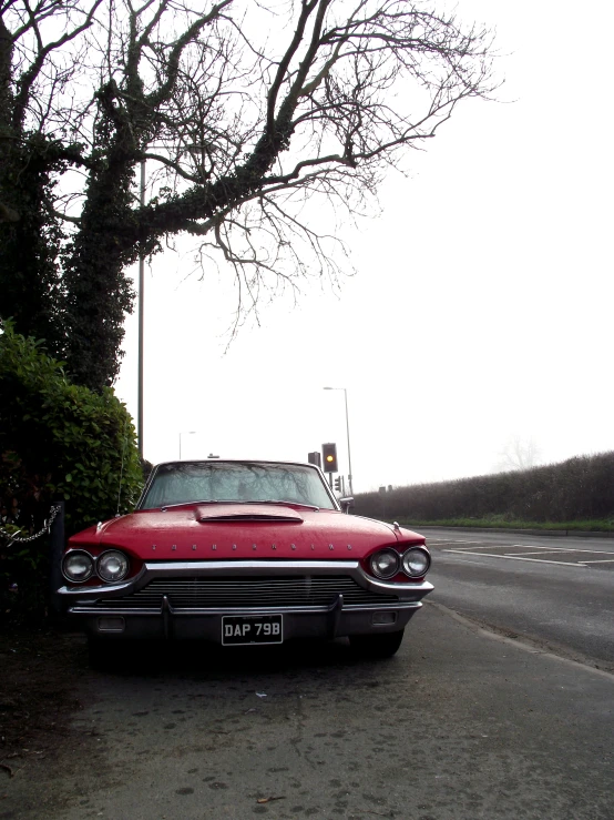 a classic red car parked next to the side of the road