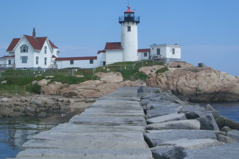 two houses on rocky area with lighthouse in background