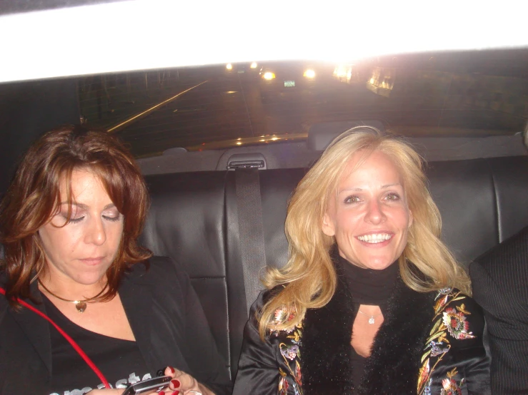 two women sitting in a car using their cell phones