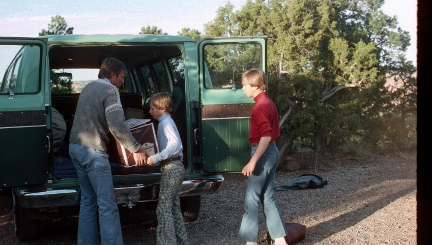 people loading the back of a green van into the passenger