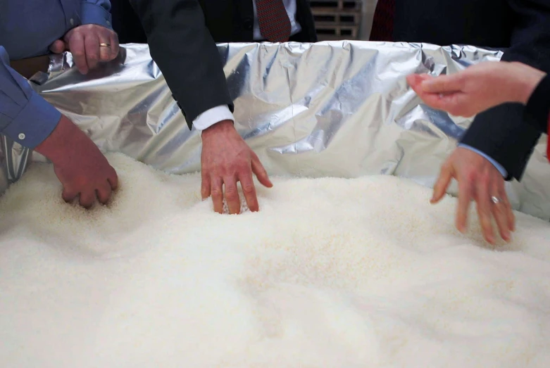 three hands reaching for food in a silver pan