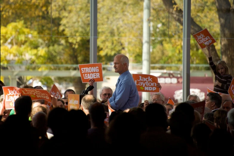 a man standing next to a crowd of people holding up signs