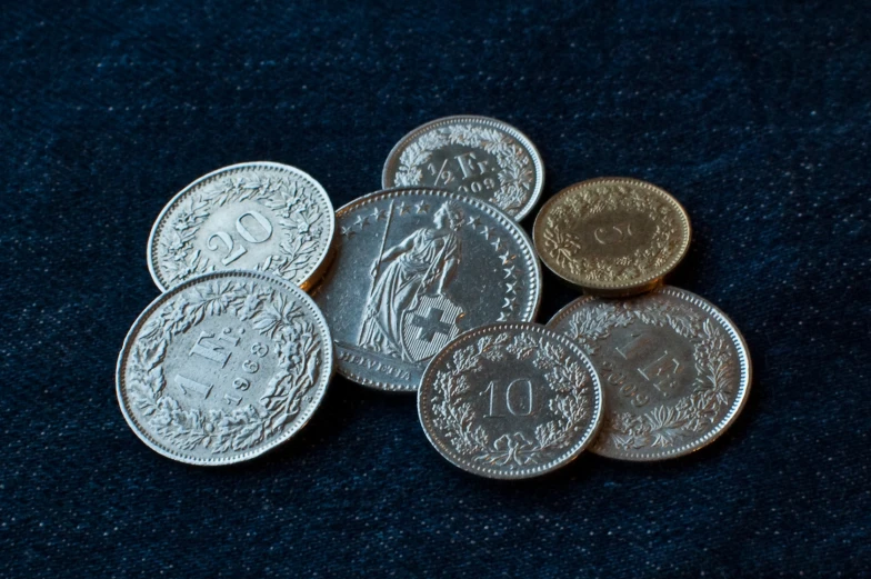 seven british coins are sitting on a blue cloth