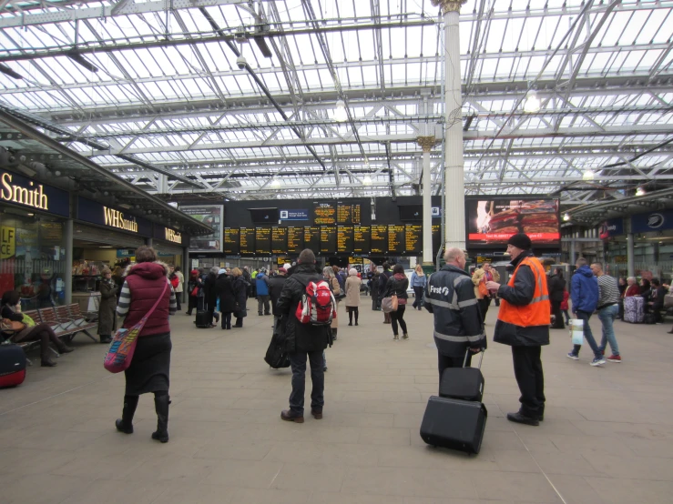 two people in jackets standing in front of some people with suitcases