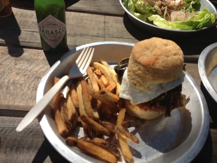 a burger and fries on a plate sitting next to some beer