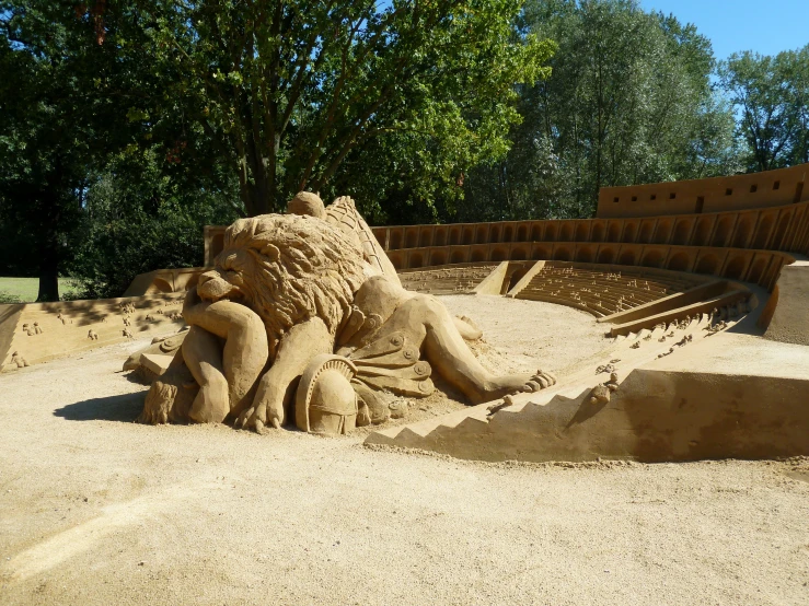 a sand sculpture of an elephant, lion, and dog laying in the middle of an empty pool