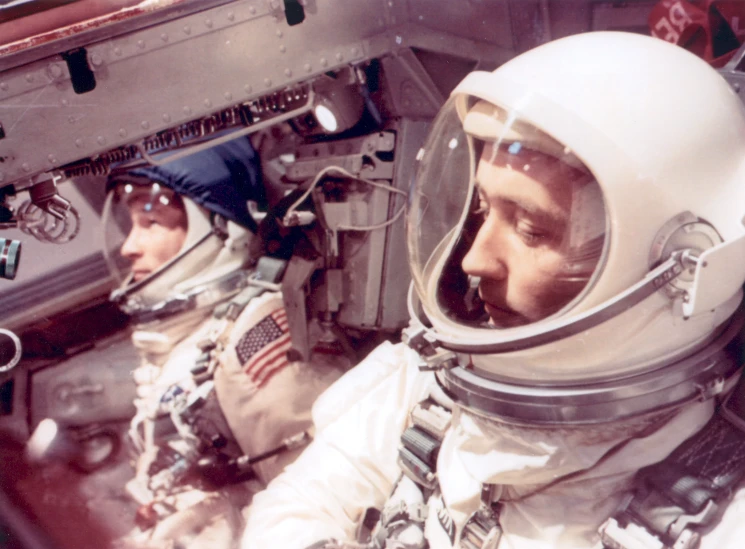 two men in space suits sitting inside a building