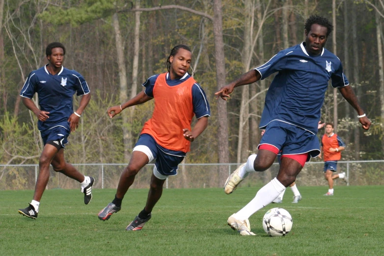 three young people playing soccer on a soccer field