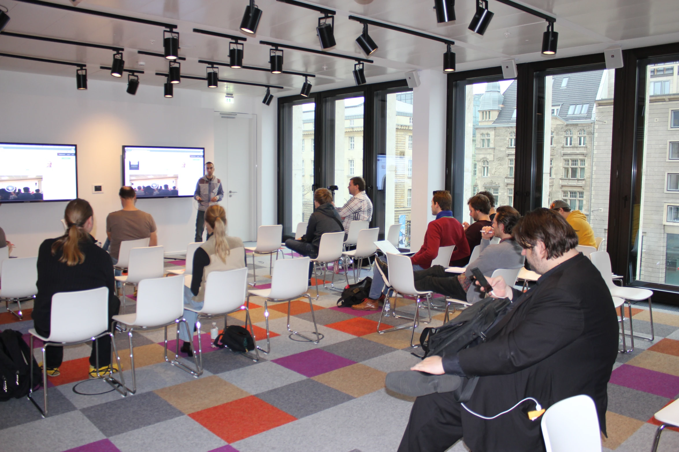 a group of people sitting on a colorful carpet watching television