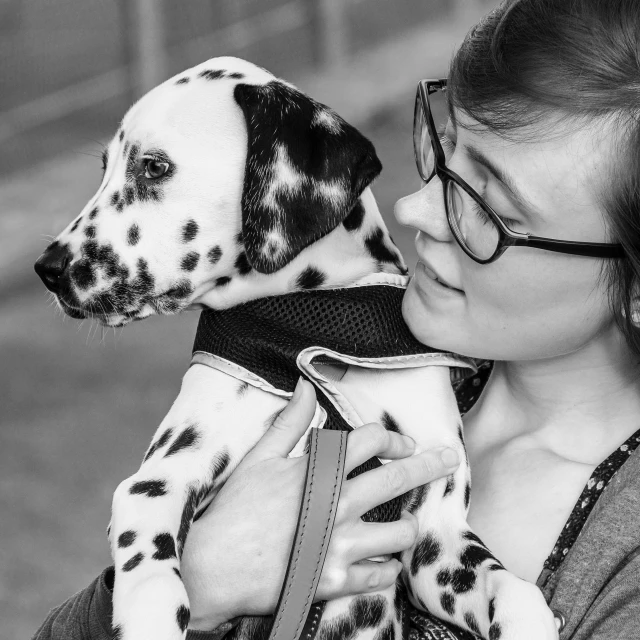 a woman with glasses hugging her dalmatian dog