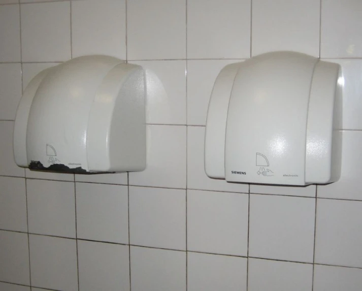 three white urinals are above tile on a wall