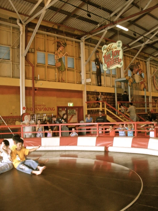 two children are sitting on the floor as they are watching a person skate