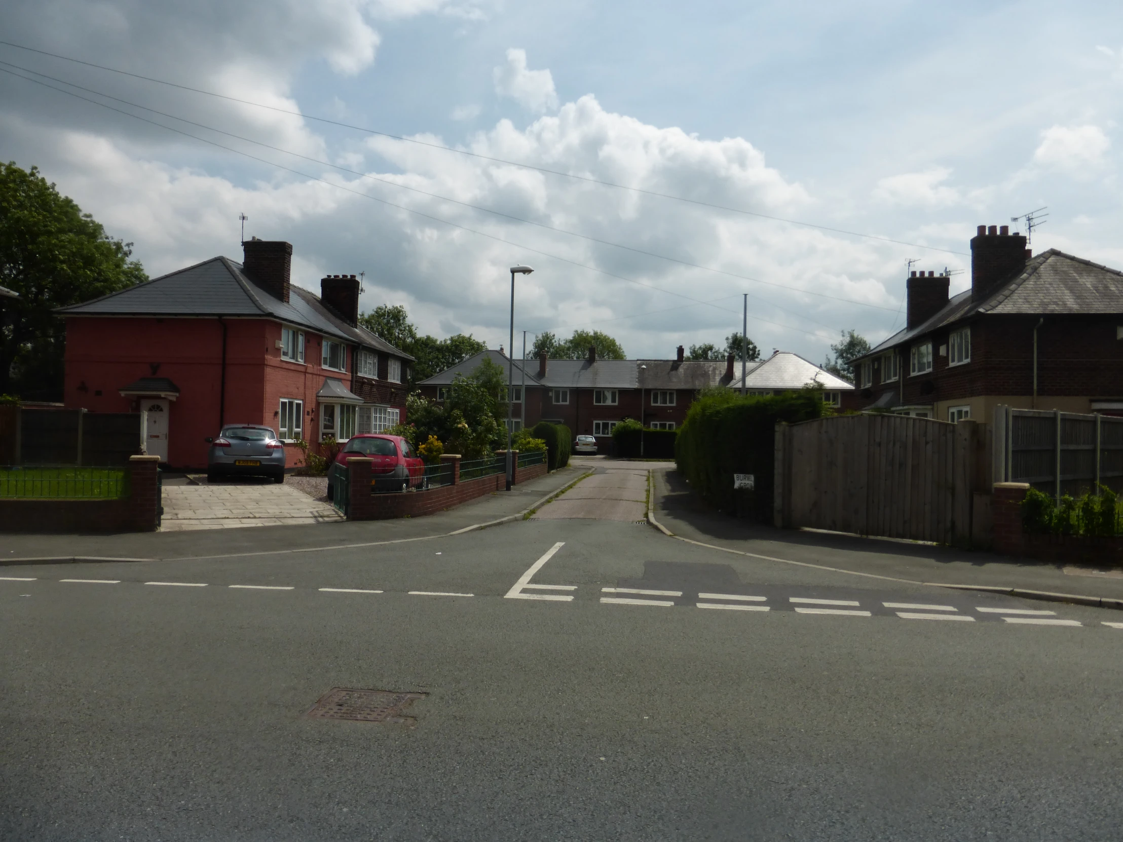 a paved street with houses next to it under cloudy skies