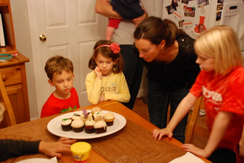 a woman with two small children around a table filled with food