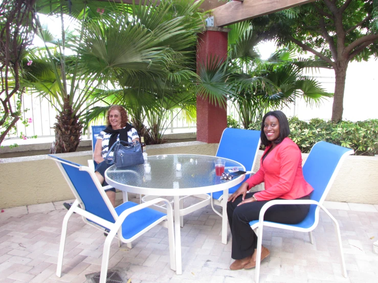 two women sitting on chairs at an outdoor table