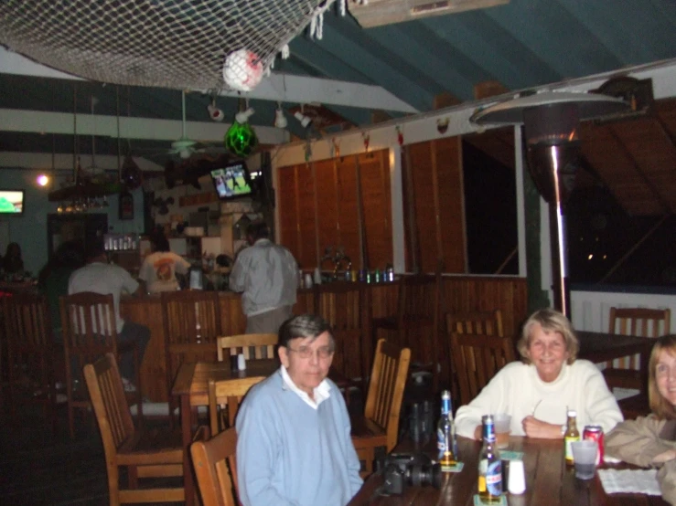 three people sitting around a wooden table at an indoor bar