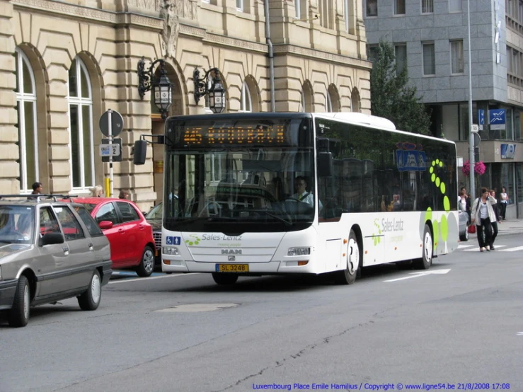 a bus driving down the road, with a lot of people on the sidewalk