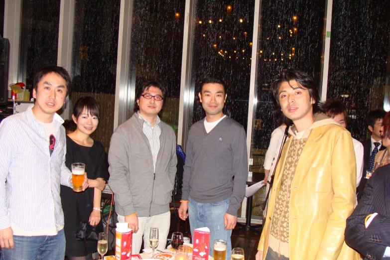 three men and a woman are holding beers