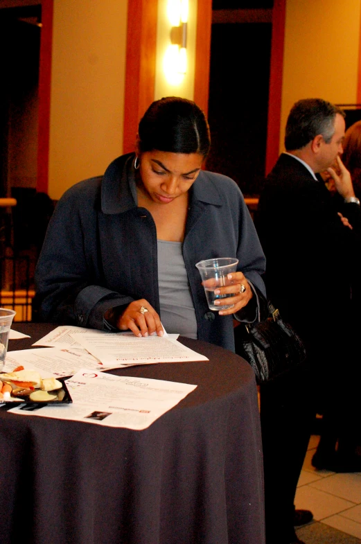 woman reading a piece of paper with a glass of water