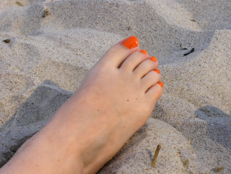 someone's feet are sitting on top of the sand