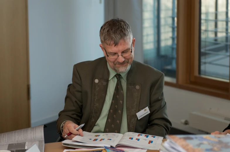 a man with a pen sitting at a table signing papers