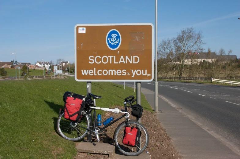 the bike is locked up by the sign for scotland