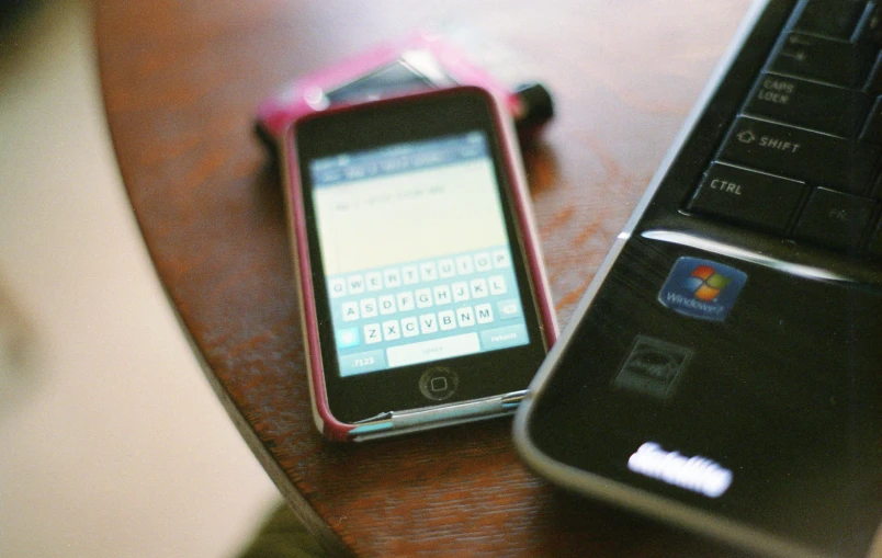 a cell phone laying on a table beside a computer