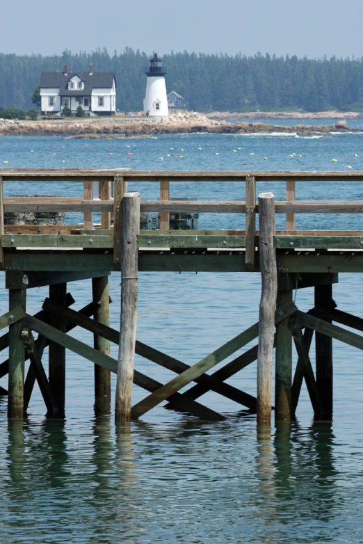two wooden posts are in the water and are under a light house