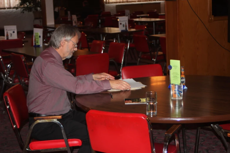 a man sitting at a table and looking at a book