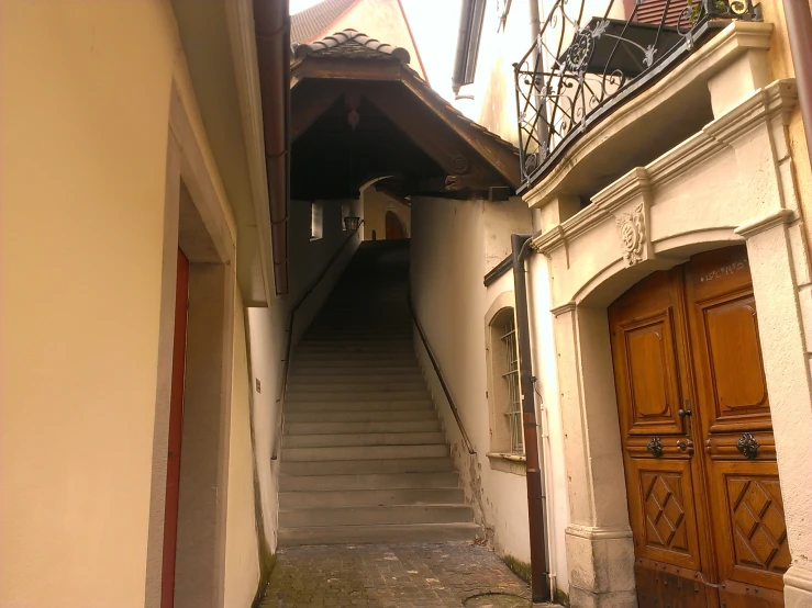 a narrow alleyway with stairs, balconys and bicycles