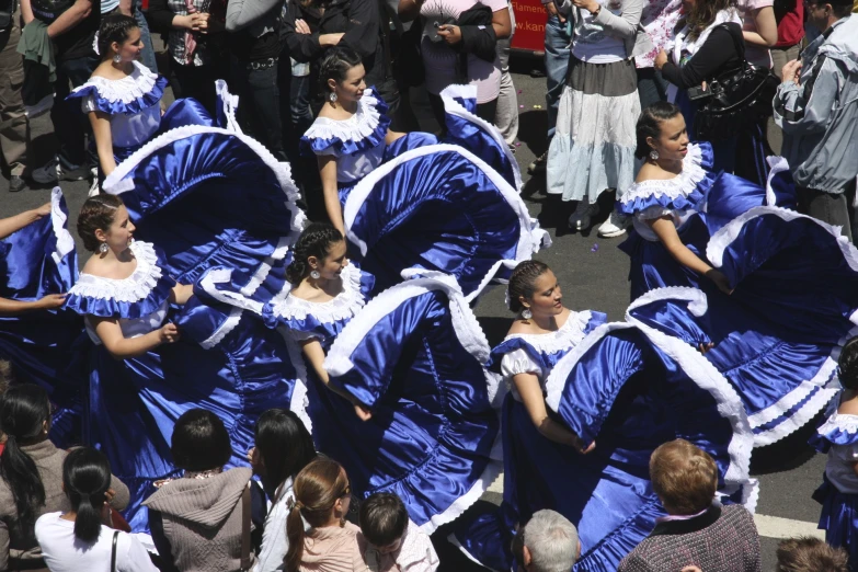 several women wearing costumes and marching through the street