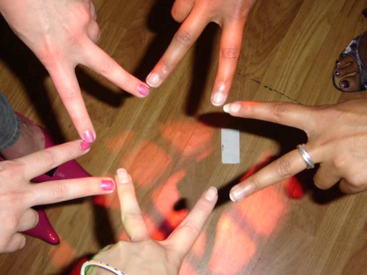 several hands holding various sized gestures on top of a wooden floor