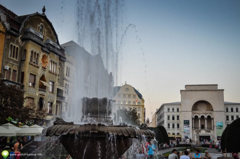 a group of people and a water fountain in the city