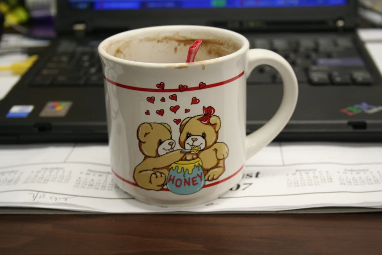 a close up of a coffee cup on a table with a laptop