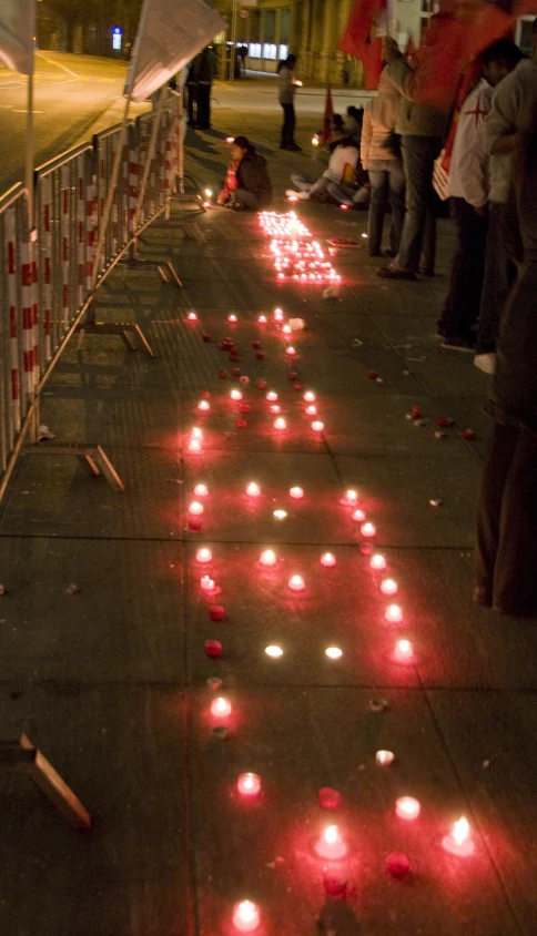 lighted candles sit on the sidewalk next to an open gate