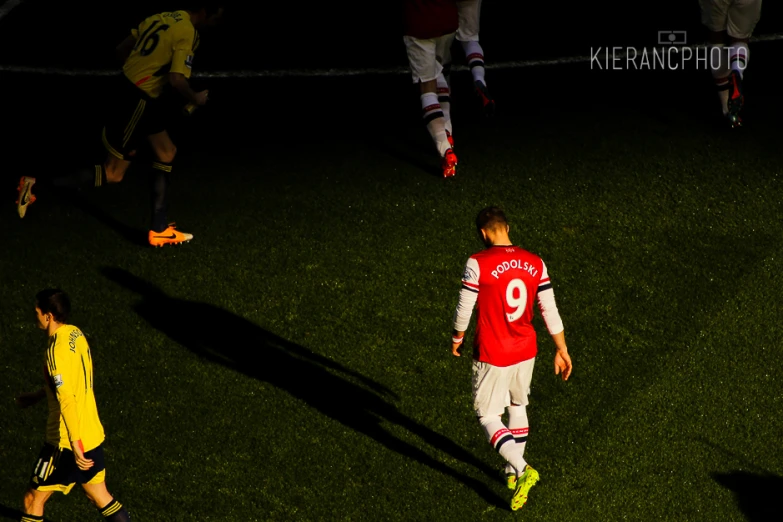 two soccer players are walking into a dark field