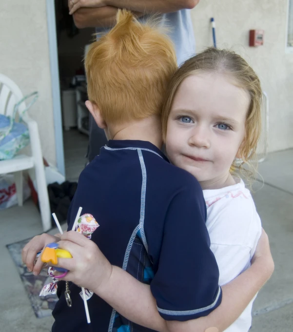 a little girl holding a little boy outside