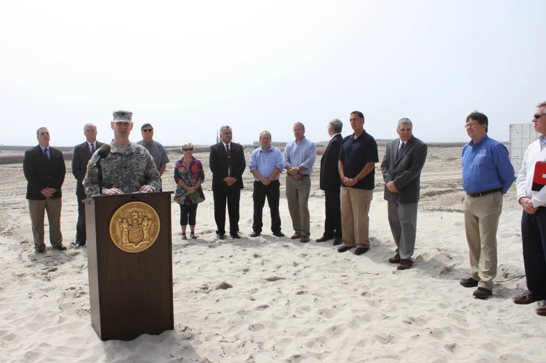 a group of men standing in the sand with their feet on a table