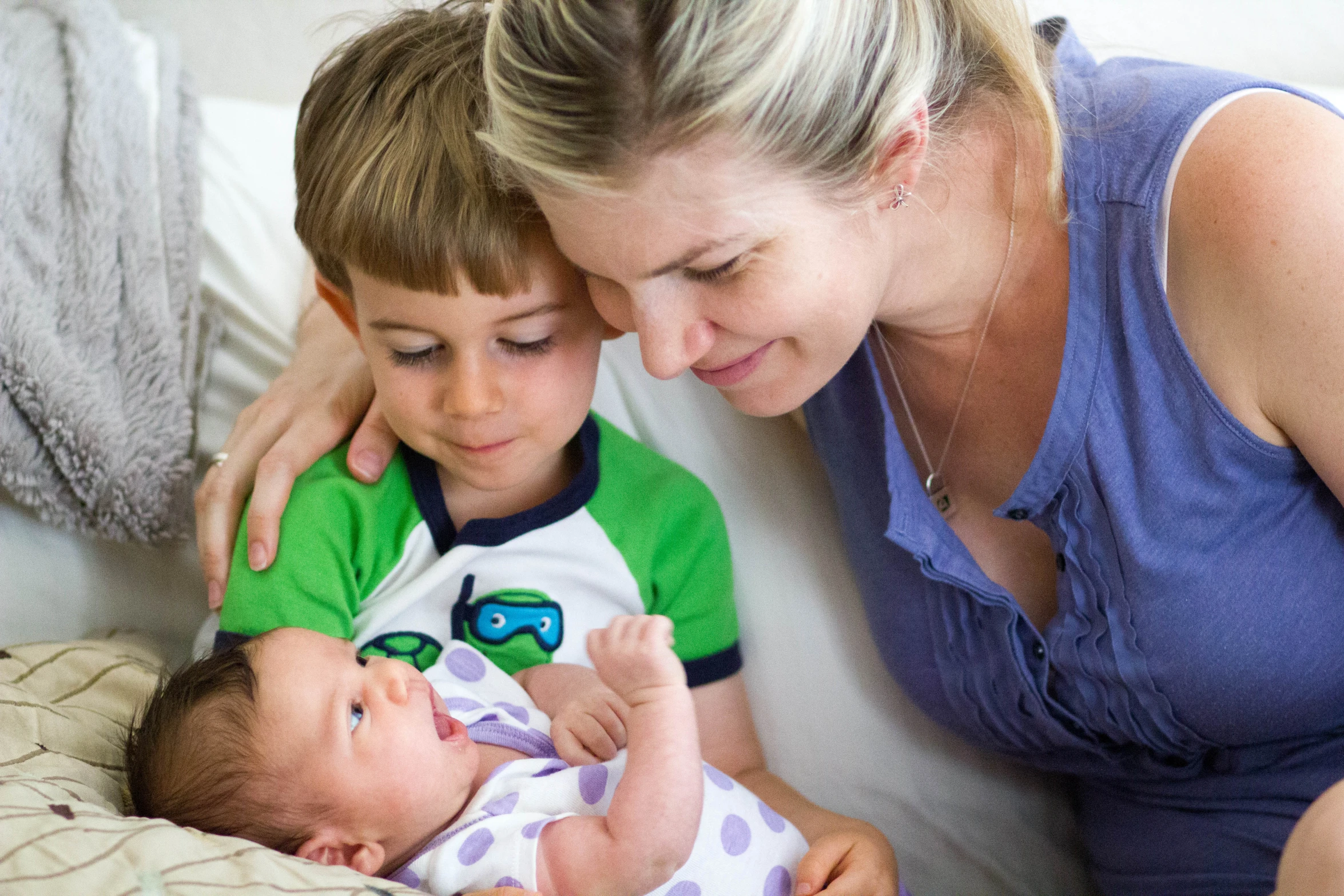 woman and boy looking down at the baby