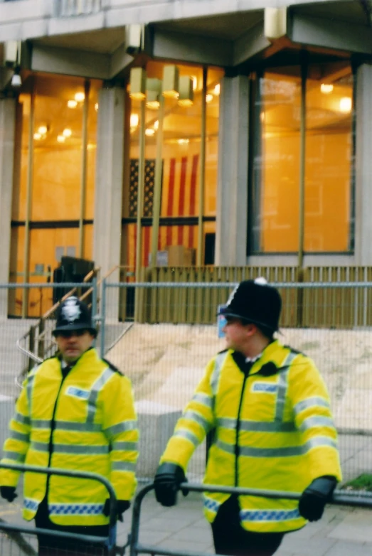 two police men in yellow jackets walking towards building