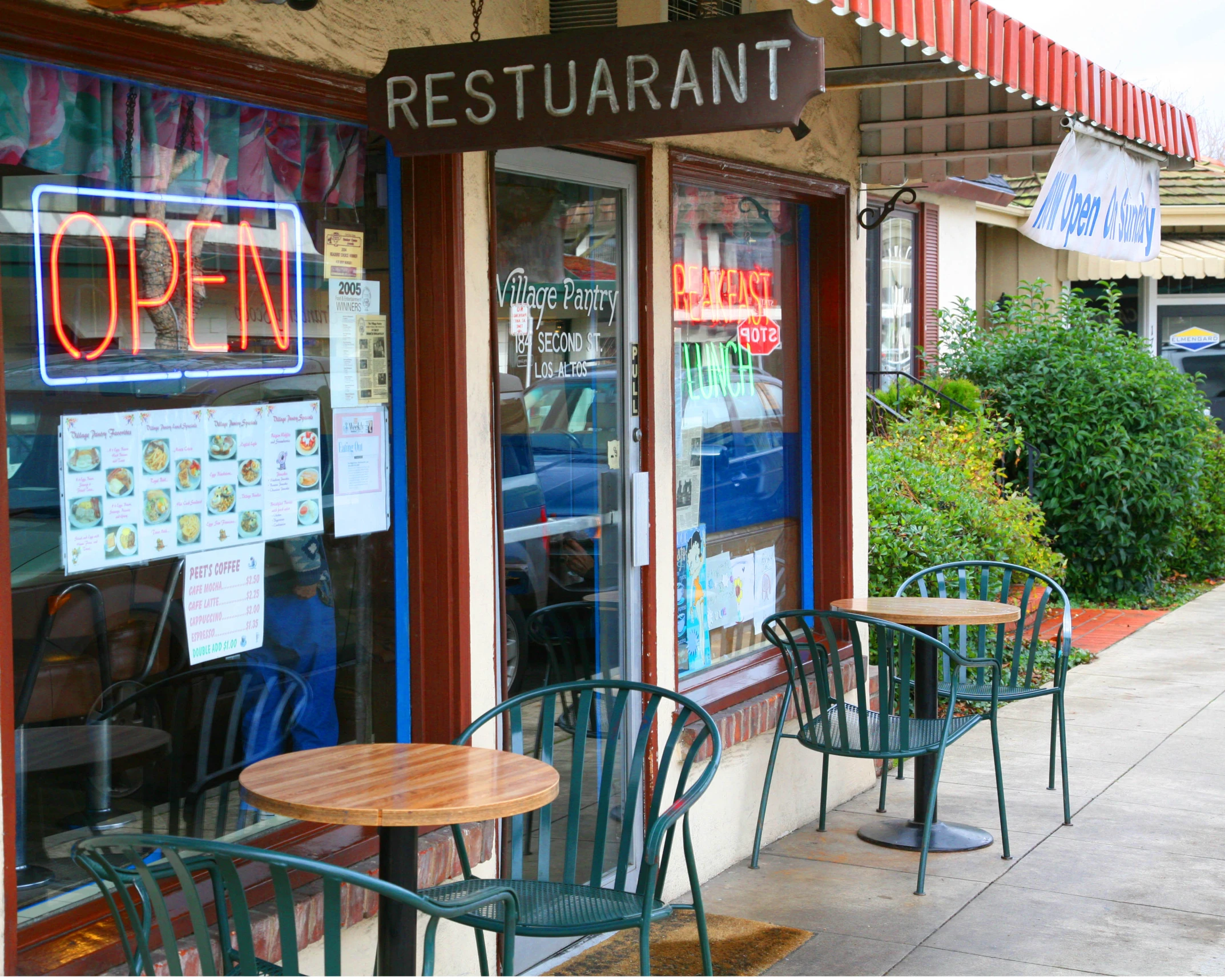 some chairs outside of a business with windows and signs