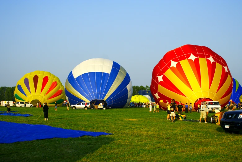 several colorful  air balloons lined up in the field