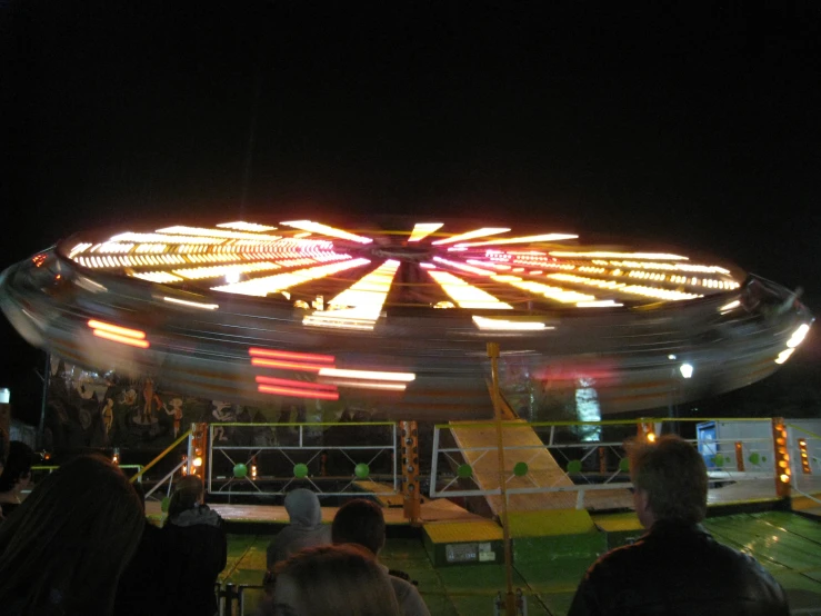 a carnival ride with people sitting on chairs at night